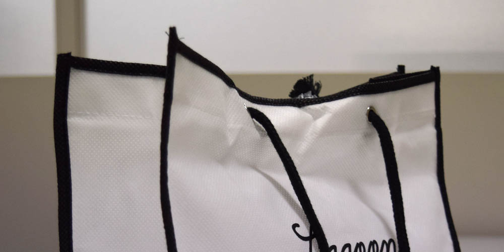 カジュアルなアパレルショップ向け。ハトメと丸紐を持ち手に使ったオリジナル不織布バッグ